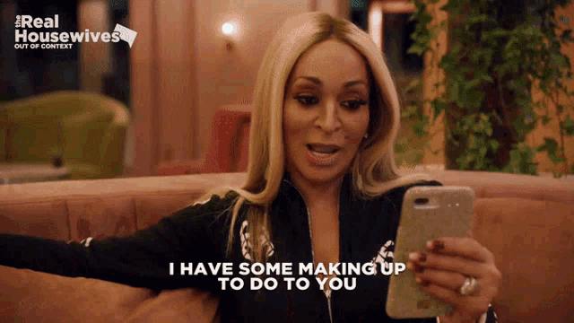 a woman sitting on a couch looking at her phone with the words i have some making up to do to you
