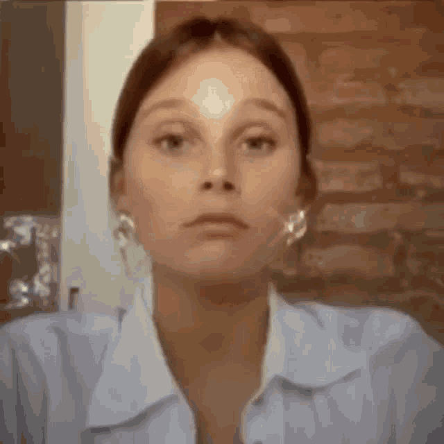 a close up of a woman 's face with a brick wall in the background