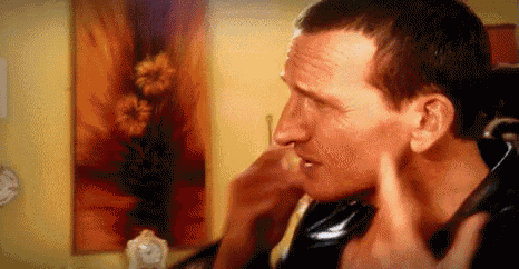 a man is holding his hand to his ear in front of a painting .