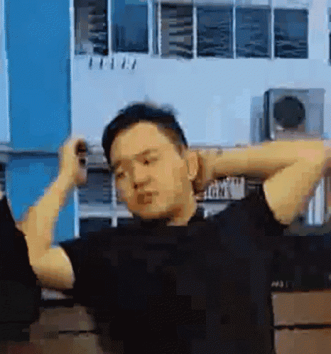 a man in a black shirt is stretching his arms in front of a building .