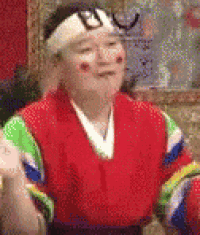 a man in a red and green costume with a headband on his head is making a funny face .