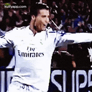 a soccer player wearing a fly emirates jersey is standing in front of a crowd .