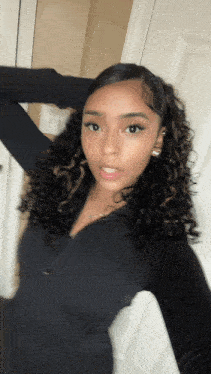 a girl with curly hair is taking a selfie