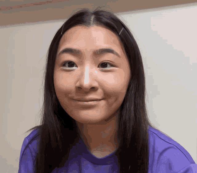 a woman with long hair wearing a purple shirt is smiling