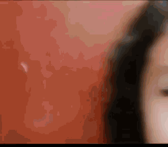a close up of a woman 's face against a red wall .