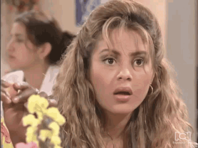 a woman with a surprised look on her face in front of flowers