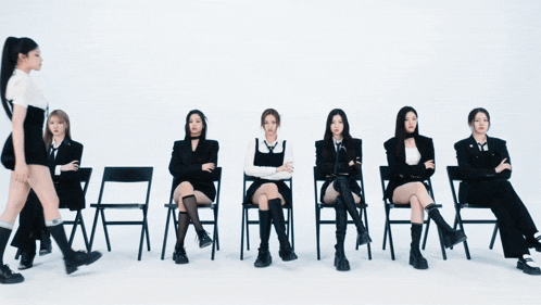 a group of women are sitting in chairs and one is walking