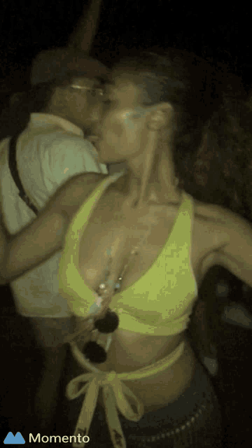 a woman in a yellow crop top is dancing with a man in a hat and the word momento is on the bottom left