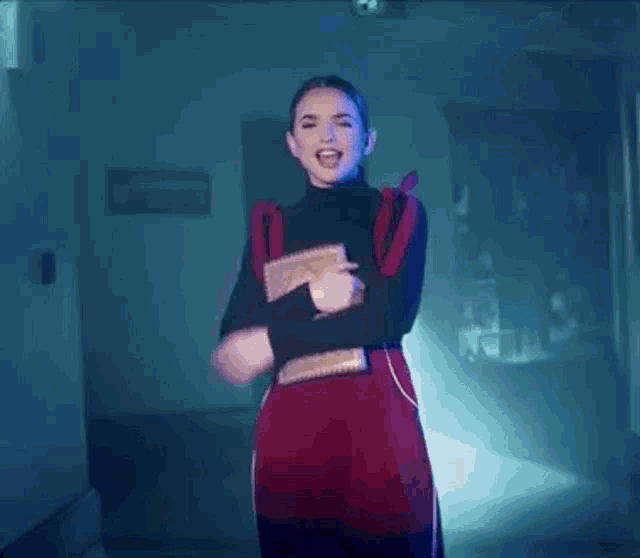 a woman in a black turtleneck is making a funny face in a blue light .