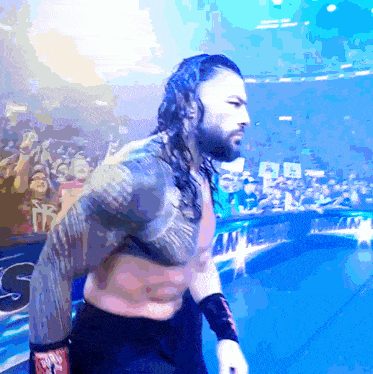 roman reigns is walking out of a wrestling ring with a crowd behind him