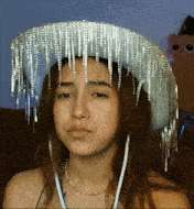 a woman wearing a cowboy hat with fringe and earrings