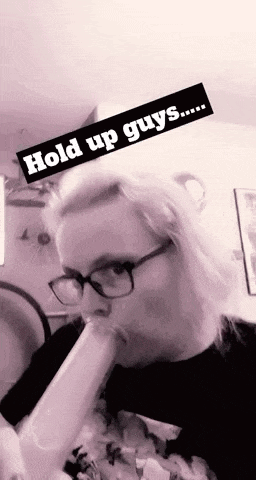a woman wearing glasses is smoking a bong in a black and white photo .