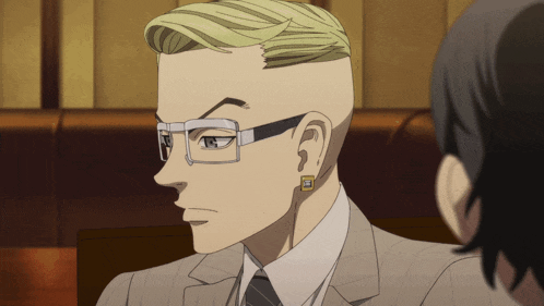 a man with a shaved head wearing glasses and earrings looks to the side