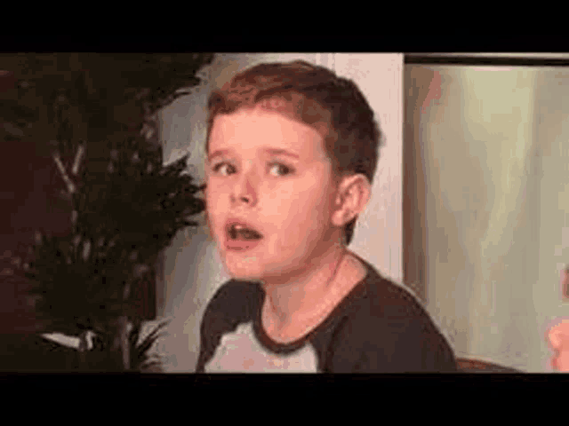 a young boy is making a funny face while sitting at a table .