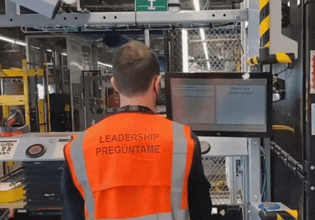 a man wearing an orange vest with leadership preguntame on it