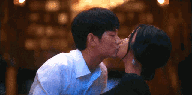 a man and woman are kissing in a dark room