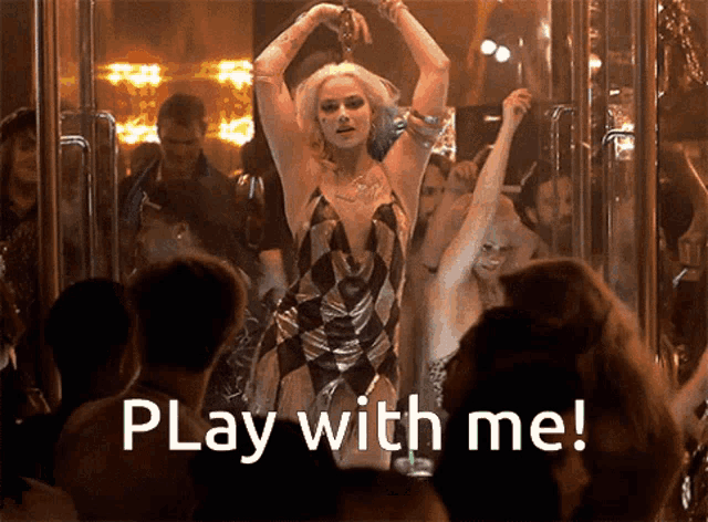 a woman in a harley quinn costume is dancing in front of a crowd with the words play with me written below her