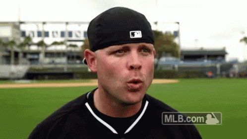 a man wearing a black hat and a mlb.com logo on his shirt