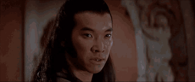 a close up of a man 's face with long hair