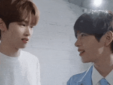 two young men are looking at each other in a room .
