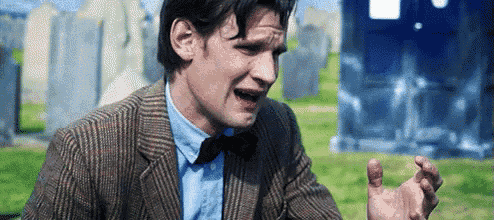 a man in a suit and bow tie is sitting in front of a cemetery .