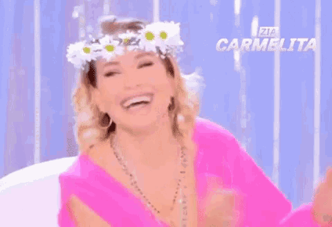 a woman wearing a flower crown and a pink shirt is laughing