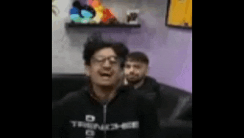 a blurry picture of a man wearing glasses and a black shirt that says ' trident ' on it .
