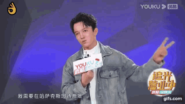 a man holding a sign that says " youku " on it