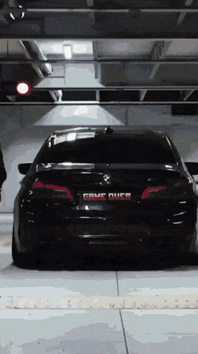 a black car is parked in a garage with a game over sign on the back