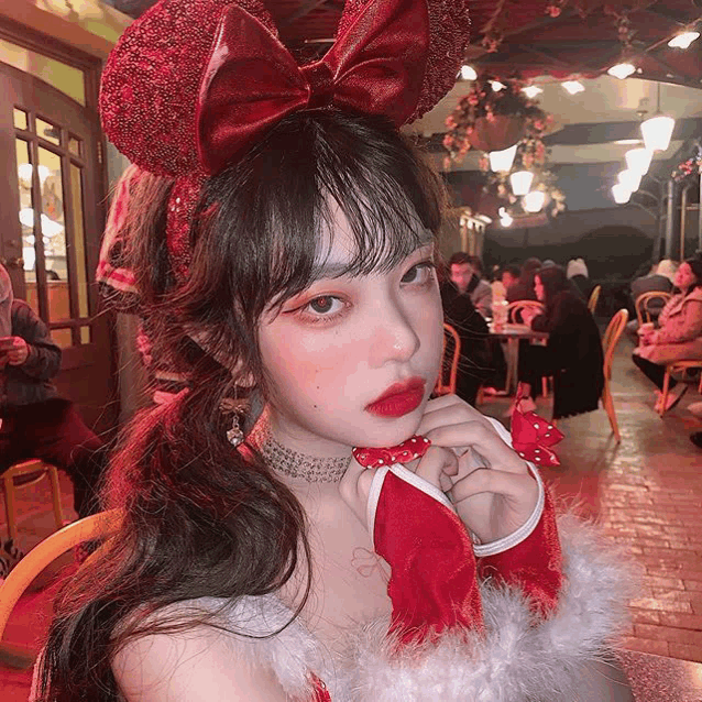 a girl with a red bow on her head is wearing a christmas costume