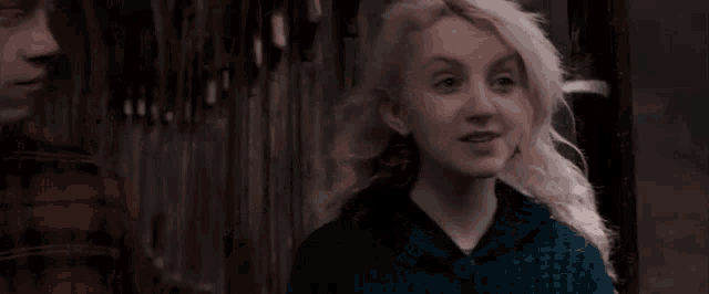 a close up of a woman with blonde hair wearing a blue sweater .