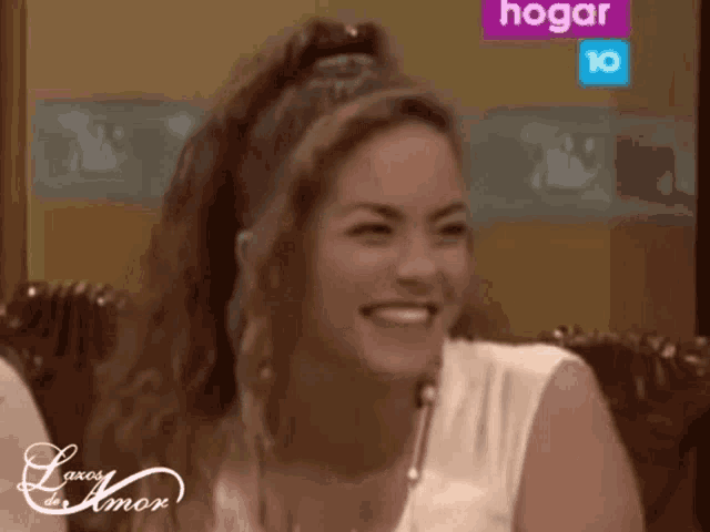 a woman smiles in front of a sign that says hogar 10
