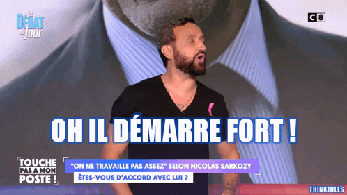 a man with a beard stands in front of a screen that says " oh il demarre fort "