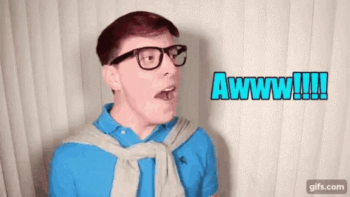 a man wearing glasses and a blue shirt is making a funny face and saying awww .