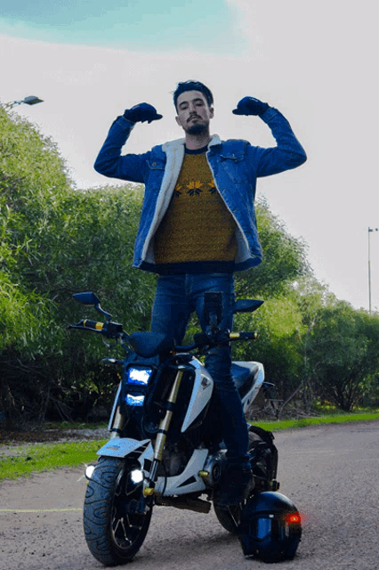 a man flexes his muscles while standing on a small motorcycle