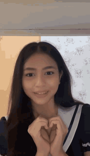 a girl making a heart with her hands and smiling