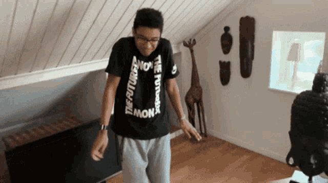 a young man wearing a black t-shirt that says the future is now