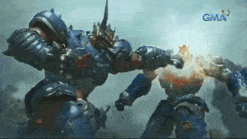 two robots are fighting each other in front of a gma sign .