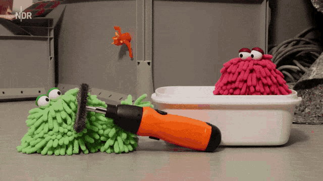 an orange screwdriver sits next to a pink monster and a green monster