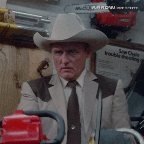 a man wearing a cowboy hat is holding a chainsaw