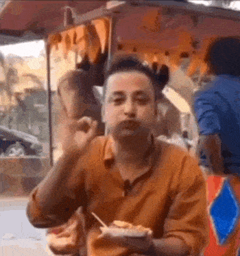 a man is sitting at a table eating food from a bowl with a fork .