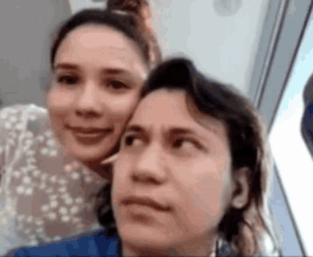 a couple of women are sitting next to each other and making funny faces .