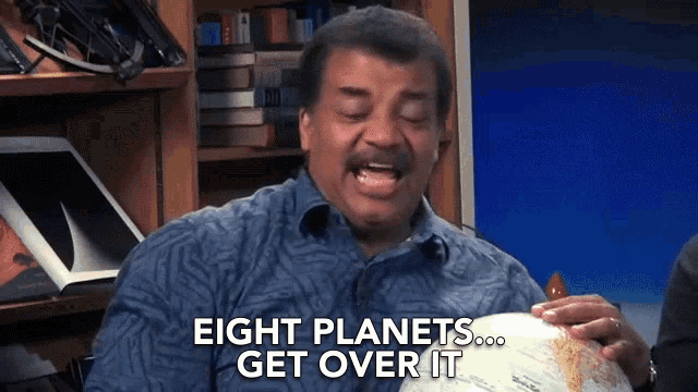 a man holding a globe with the words eight planets get over it