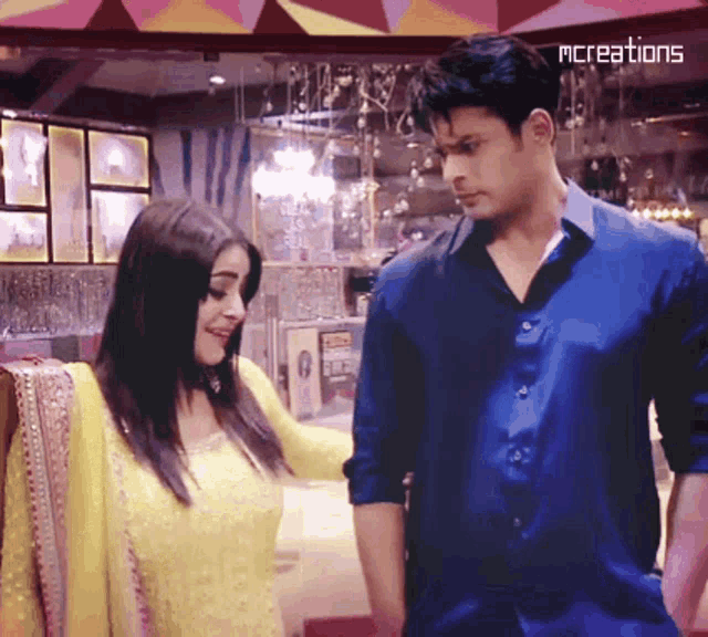 a man in a blue shirt is standing next to a woman in a yellow dress ..