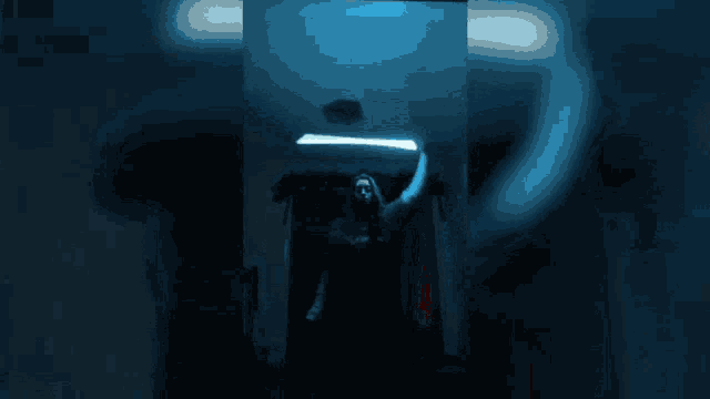 a person in a dark room with a blue light behind them