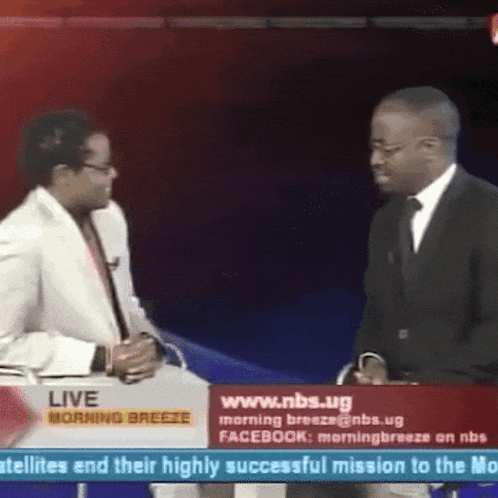 a man in a suit talks to a woman in a white suit on a live morning breeze show