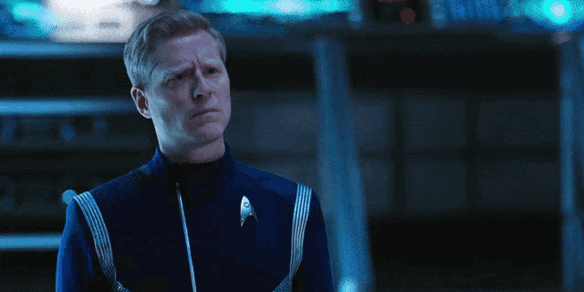a man in a star trek uniform stands in front of a screen that says oh fuck
