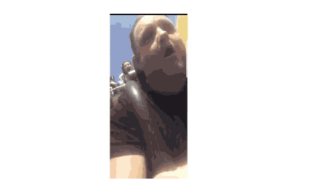 a man in a black shirt is riding a roller coaster with a woman in the background .