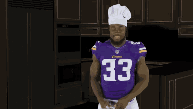 a man wearing a purple jersey with the number 33 on it is in a kitchen