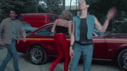 a man and a woman are dancing in front of a red car that says bfgoodrich on it